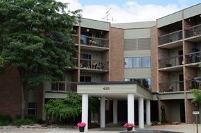Alma townhouse for rent - Apartment building with balconies and flower pots in front.