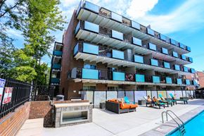 Denver apartment for rent - an apartment building with a pool and lounge chairs in front of it