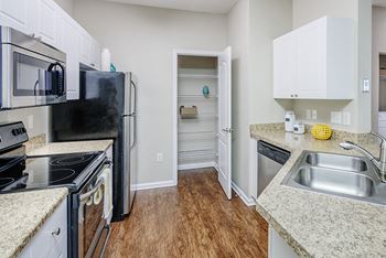 Premium finishes including stainless steel appliances, granite-look countertops, ceiling fans, wood-style flooring in kitchens and faux-wood blinds