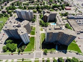 Hamilton apartment for rent - A large building with a curved facade is situated in a parking lot.