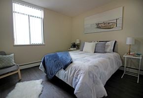 Hamilton apartment for rent - A bedroom with a bed, a chair, a lamp, and a painting on the wall.