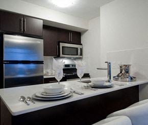 Toronto apartment for rent - A kitchen with a stainless steel refrigerator, microwave, and white countertop.