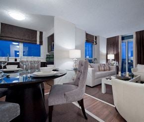 Toronto apartment for rent - A modern dining room with a table set for two and a couch in the background.