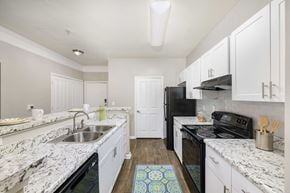 Gainesville apartment for rent - A kitchen with white cabinets and a black fridge.