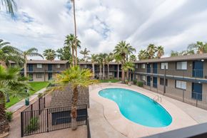 Phoenix apartment for rent - a resort style swimming pool in front of a building with palm trees