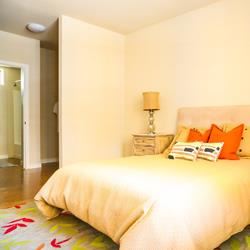 Emeryville apartment for rent - A bed with a white headboard and a white pillow is in the foreground of the image.