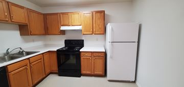 Powell apartment for rent - a kitchen with wood cabinets and black appliances and a white refrigerator