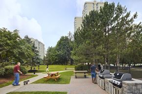 Brampton apartment for rent - people walking around a park with bbq pits and picnic tables