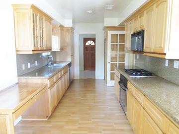 Los Angeles apartment for rent - A kitchen with wooden cabinets and a brown door in the background.