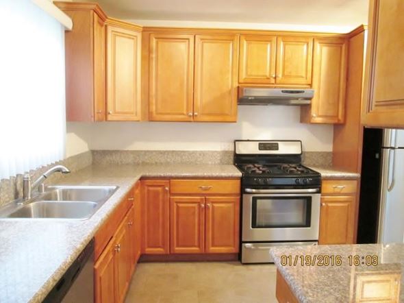 Los Angeles apartment for rent - A kitchen with wooden cabinets and a stove top oven.