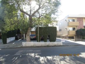 Los Angeles apartment for rent - a street with a tree and a fence in front of an apartment building