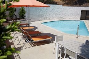 Sherman Oaks apartment for rent - a pool with chairs and an umbrella next to a pool