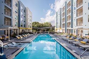 Pittsburgh apartment for rent - A swimming pool surrounded by lounge chairs and buildings.