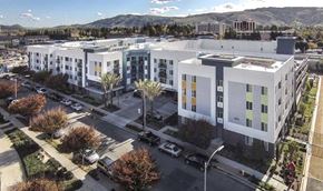 San Jose apartment for rent - A large white building with a parking lot in front of it.