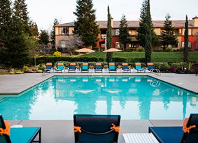 Rocklin apartment for rent - A pool with chairs around it and a building in the background.