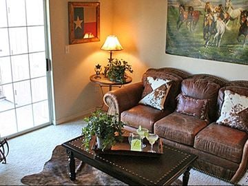Waco apartment for rent - A living room with a brown couch, a table with a tray on it, and a painting on the wall.