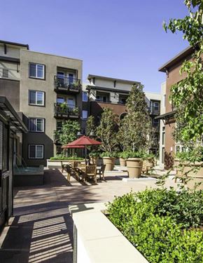 San Jose apartment for rent - A sunny day at a courtyard with a red umbrella and potted plants.