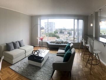 San Mateo apartment for rent - A living room with a white couch, grey armchairs, and a coffee table in front of a large window.