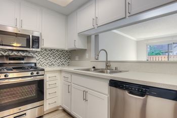 Renovated kitchen featuring white cabinet, countertops and stainless steel appliances.