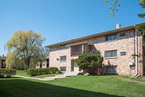 Bloomington apartment for rent - a brick apartment building with a green lawn and a blue sky