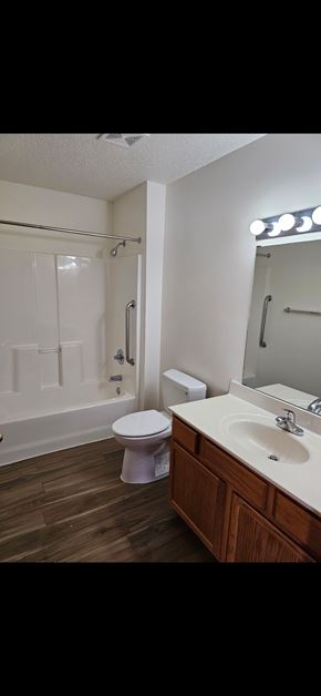 Grand Forks apartment for rent - A white toilet sits in a bathroom next to a sink and a bathtub.