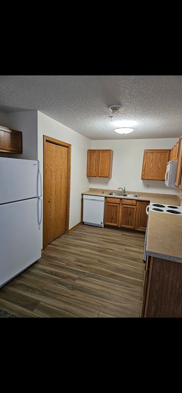 Grand Forks apartment for rent - A kitchen with wooden cabinets and a white refrigerator.