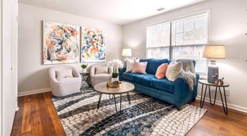Huntsville triplex for rent - A living room with a blue couch, a white chair, and a coffee table with a vase of flowers on it.