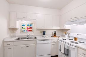 Huntsville triplex for rent - A white kitchen with a stove, sink, and cabinets.