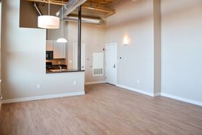 Lowell apartment for rent - A room with a kitchen area in the background and a doorway leading to another room.
