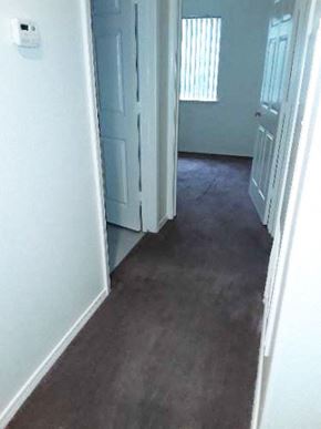 Planada apartment for rent - Image of carpeted hallway, and two doors to bathroom and bedroom
