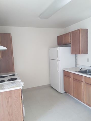Kallispell apartment for rent - an empty kitchen with white appliances and wooden cabinets
