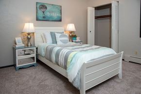 Fridley apartment for rent - a bedroom with a bed and a nightstand with two lamps and a painting