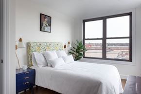 Brooklyn apartment for rent - A bedroom with a large bed and a window overlooking a cityscape.
