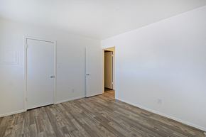 Tempe apartment for rent - a bedroom with white walls and wood flooring and a closet