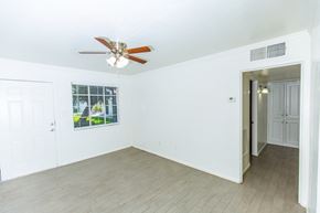 Phoenix apartment for rent - an empty living room with a ceiling fan and a door to a hallway