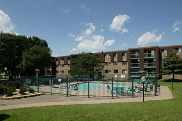 Coon Rapids apartment for rent - a view of a pool with a fence in front of an apartment building