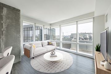 Boston apartment for rent - A modern living room with a white sofa and a large window overlooking the city.