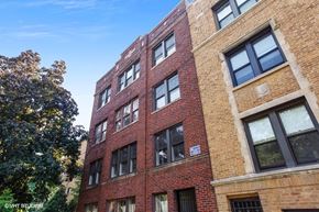 Chicago apartment for rent - a large brick building with many windows and a tree