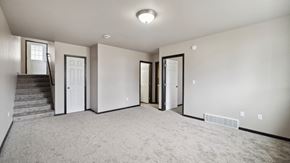 Fargo townhouse for rent - A spacious room with a staircase and a carpeted floor.