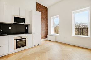 Brooklyn apartment for rent - A kitchen with white cabinets and a brick wall.