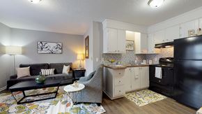 Greenville apartment for rent - A black fridge sits in a kitchen with white cabinets and a black couch with pillows.