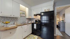 Greenville apartment for rent - A black refrigerator in a kitchen with white cabinets.