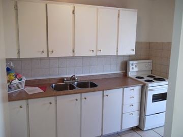 North York apartment for rent - A kitchen with white cabinets and a white stove.