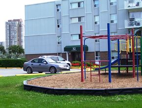 North York apartment for rent - A playground with a slide and a car parked in front of a building.