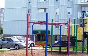 North York apartment for rent - A playground with a red and blue structure in front of a building with the number 32 on it.