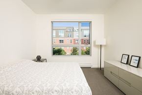 Winooski apartment for rent - Room with bed, lamp, and dresser with window overlooking Winooski Falls Way