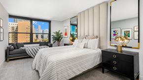 Chicago apartment for rent - A bedroom at Eleven Thirty. A sofa bench sits beneath the window behind a large, comfortable bed.
