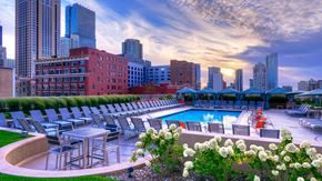 Chicago apartment for rent - Looking over a row of white floors at the pool deck at dusk. The sun is setting ahead and there are city building all around.