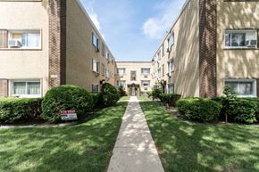 Chicago apartment for rent - a walkway between two brick apartment buildings with grass and bushes