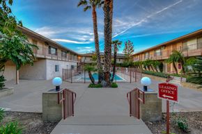 Orange apartment for rent - a building with a swimming pool and palm trees in front of it